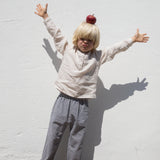 Barn iført beige skjorte og ternet bukser 
