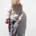 Barn iført beige skjorte og ternet bukser 