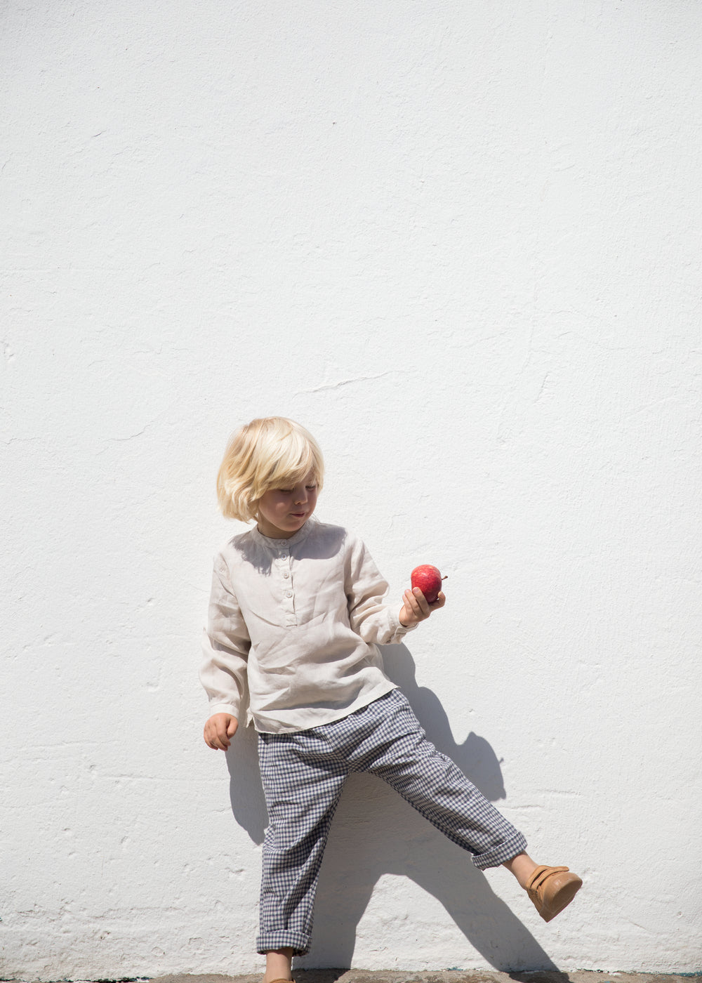 Barn iført beige skjorte og ternet bukser 