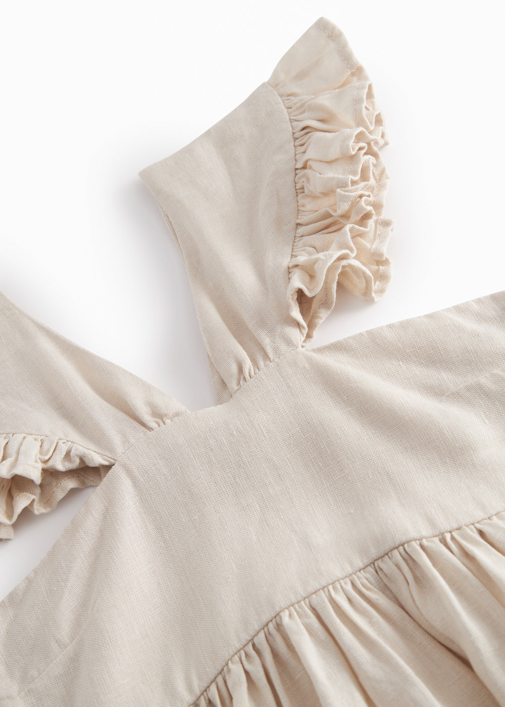 Ærmeløs beige kjole til børn med brede stropper og flæser på skulderen og smock bagpå