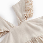 Ærmeløs beige kjole til børn med brede stropper og flæser på skulderen og smock bagpå