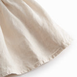 Ærmeløs beige kjole til børn med brede stropper og flæser på skulderen og smock bagpå