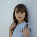 Barn iført lys blå kjole med flæseærmer