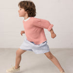 Barn iført stribet bluse og lyse shorts