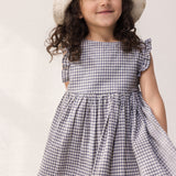 Barn iført ternet kjole med flæser og sommerhat