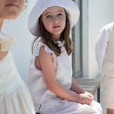 Barn iført lys top, nederdel og sommerhat