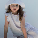 Barn iført lys top, nederdel og sommerhat