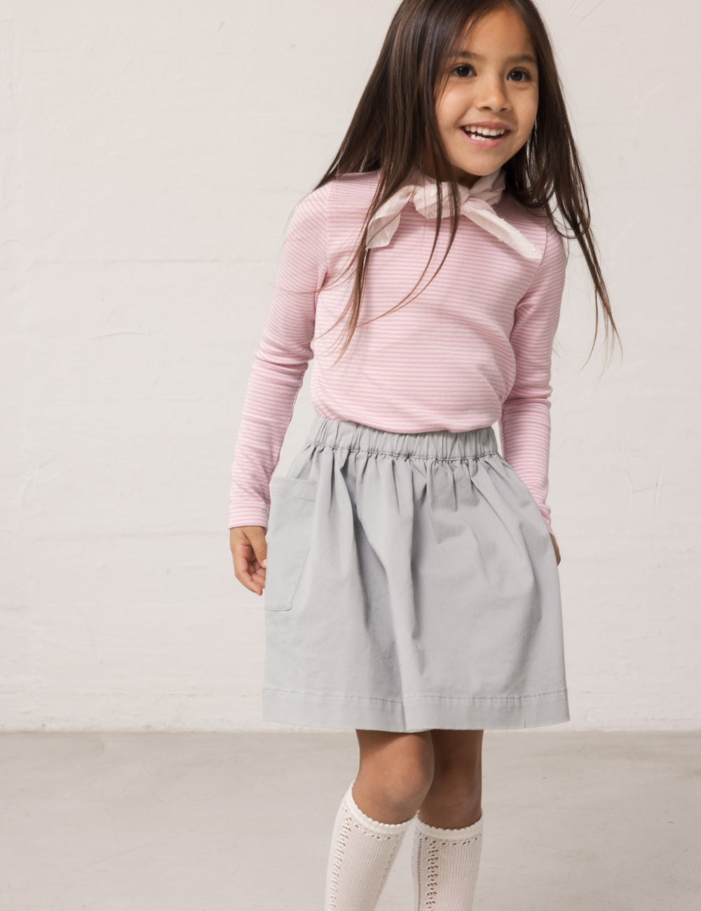 Pige iført blå chino nederdel og lyserød t-shirt