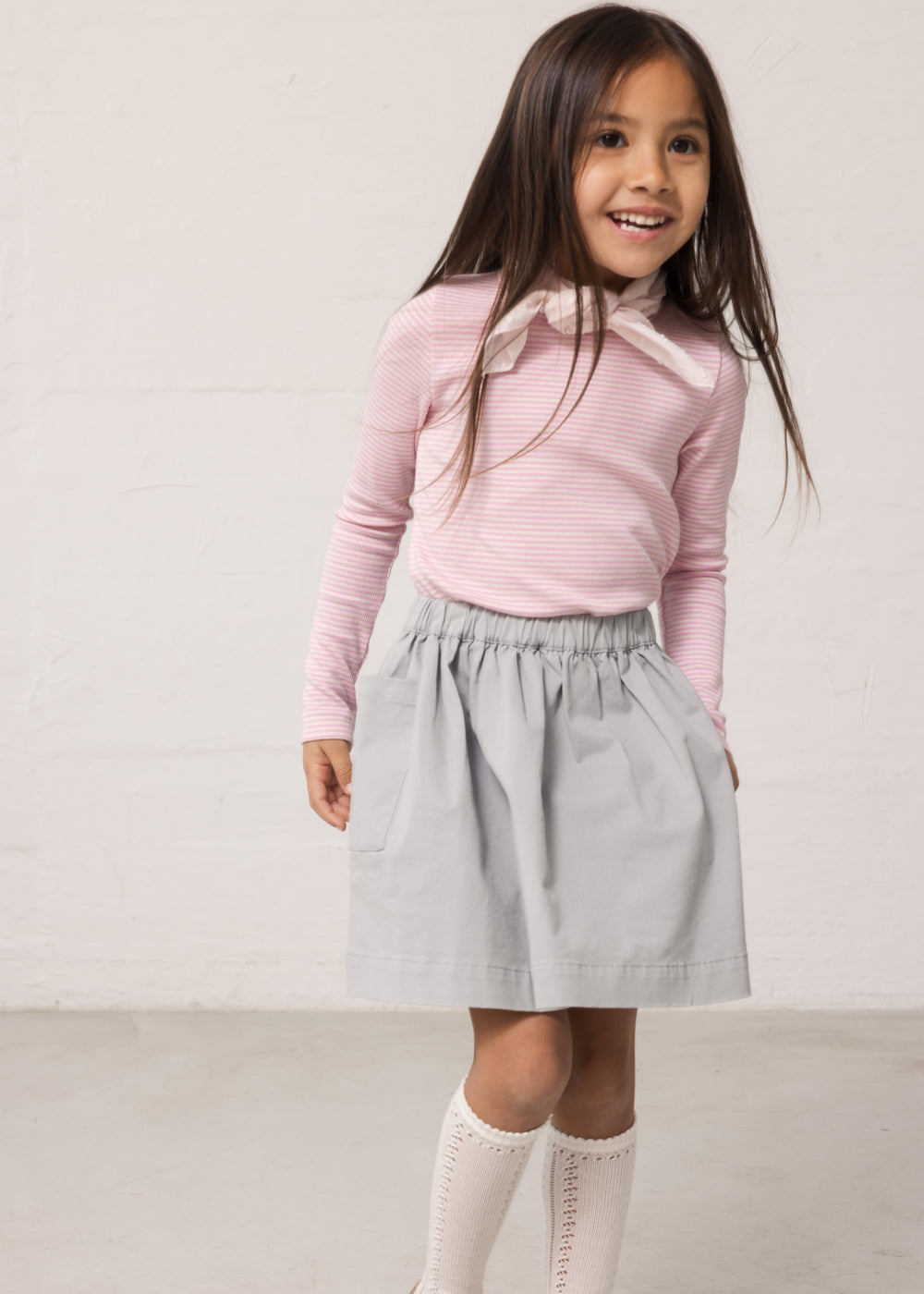 Pige iført blå chino nederdel og lyserød t-shirt