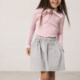 Pige iført blå chino nederdel og lyserød t-shirt