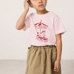 Pige iført grøn chino nederdel og lyserød t-shirt