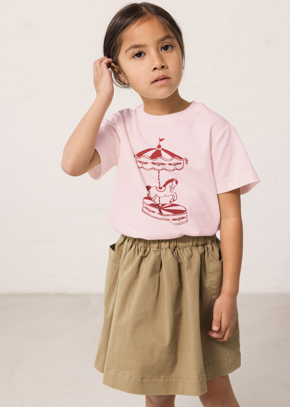 Barn iført lyserød T-shirt med print og nederdel