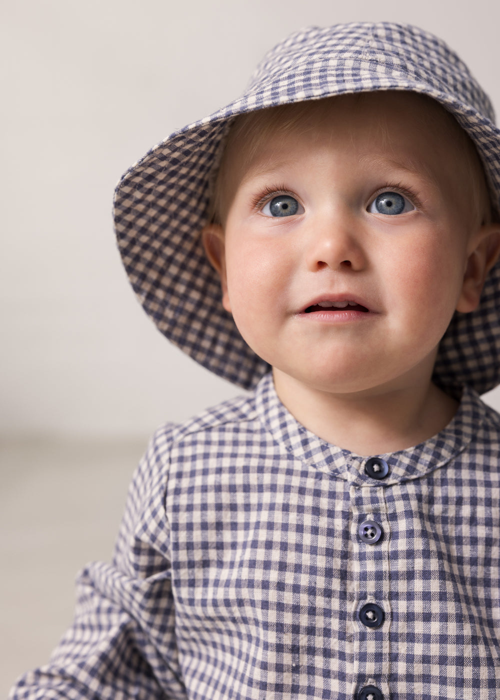 Baby iført langærmet ternet skjorte med kinakrave og hat