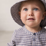 Baby iført langærmet ternet skjorte med kinakrave og hat