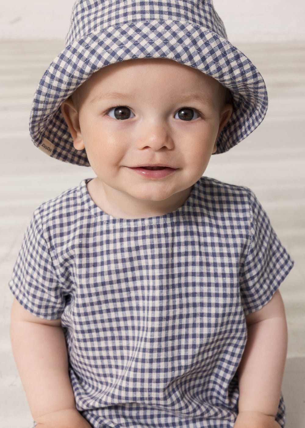 Baby iført bollehat og ternet sæt