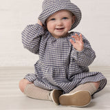 Baby iført langærmet ternet kjole og hat