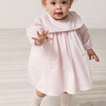 Baby iført lyserød kjole med krave og lange ærmer