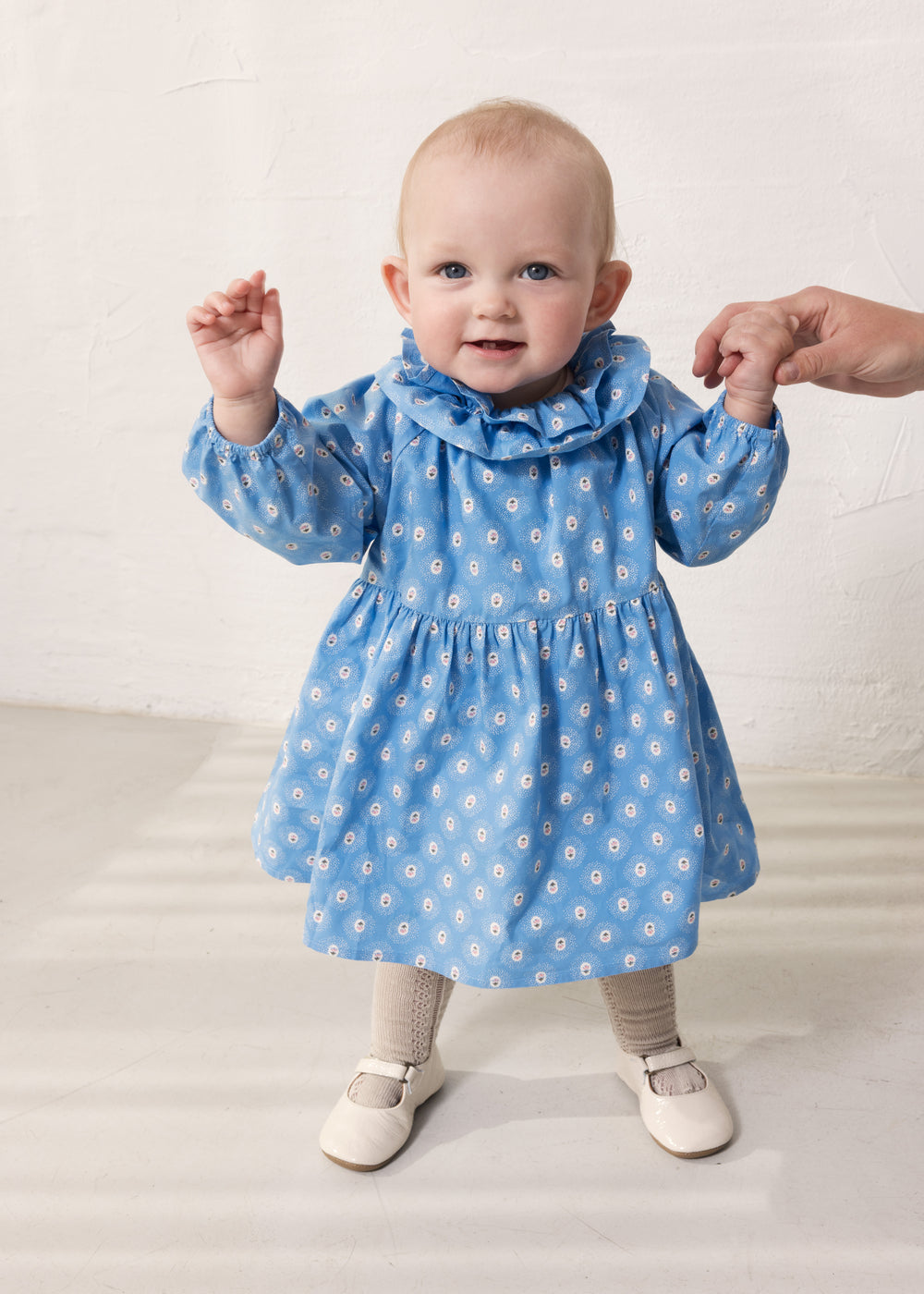 Baby iført blå kjole med små blomster