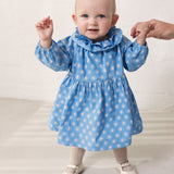 Baby iført blå kjole med små blomster