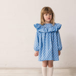 Barn iført blå kjole med blomsterprint og flæsedetalje