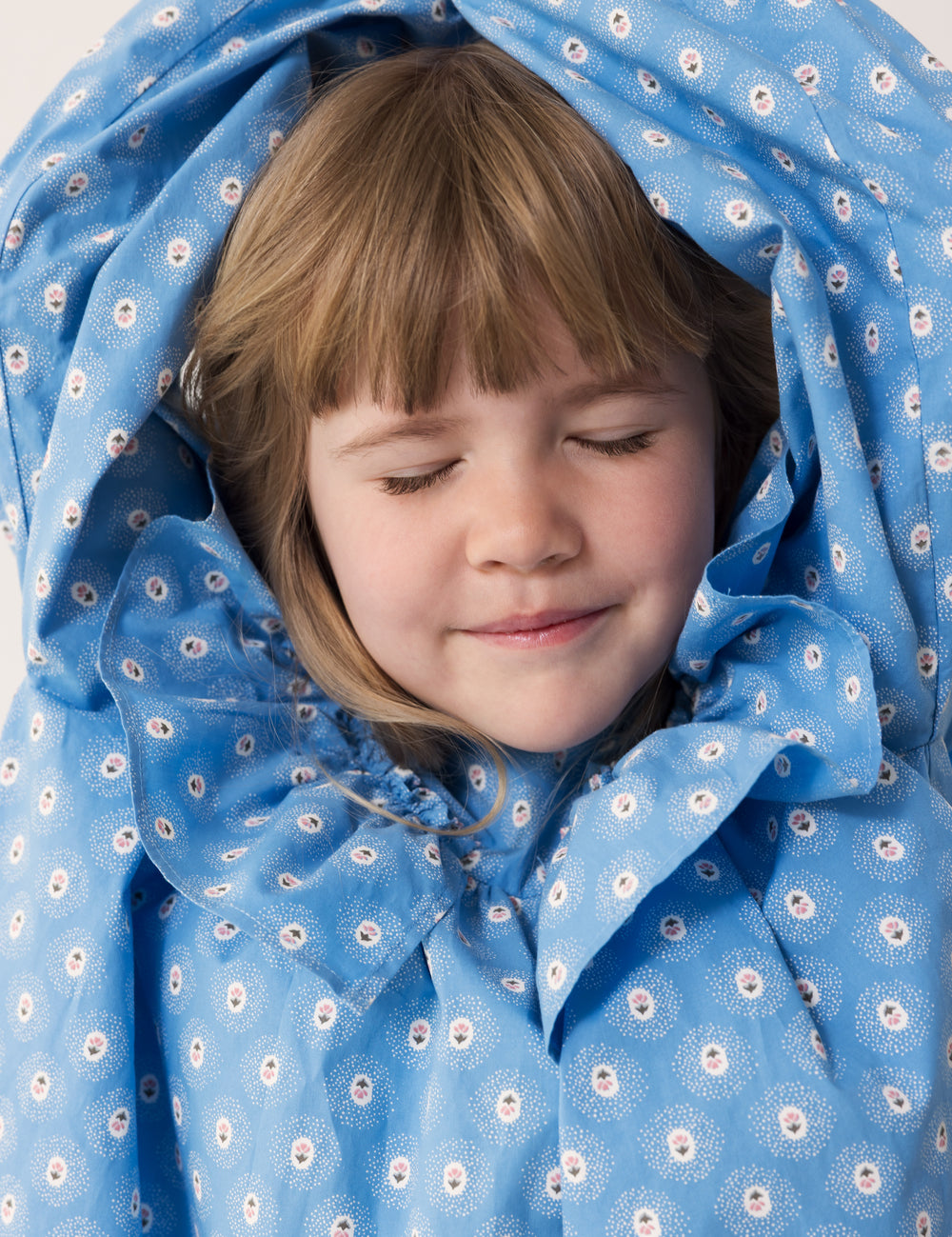 Barn iført blå kjole med blomsterprint og flæsedetalje