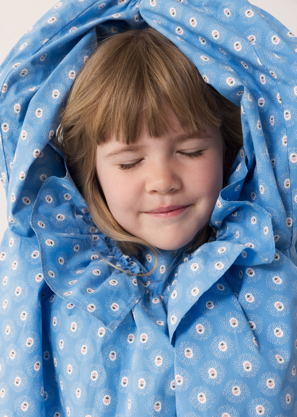 Barn iført blå kjole med blomsterprint og flæsedetalje