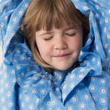 Barn iført blå kjole med blomsterprint og flæsedetalje