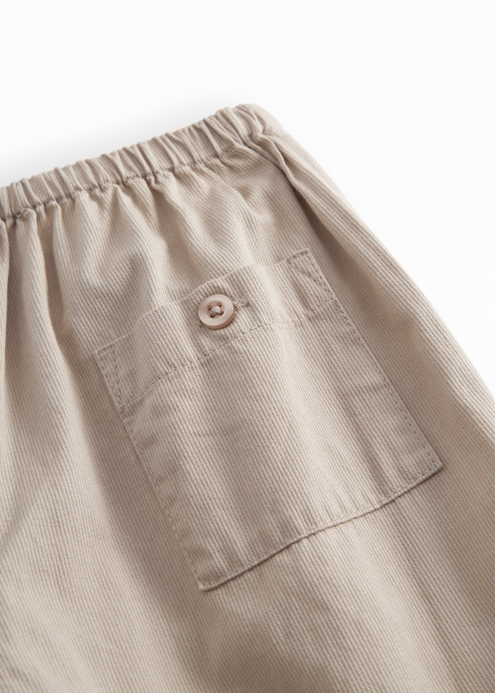 Grå bukser til baby med en løs pasform, lomme bagpå samt elastik i taljen