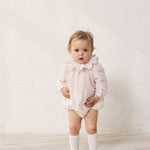 Baby iført lyserød heldragt med lange ærmer og flæsekrave