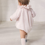 Baby iført lyserød heldragt med lange ærmer og flæsekrave