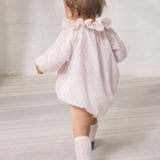 Baby iført lyserød heldragt med lange ærmer og flæsekrave