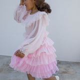 Pige iført lyserød langærmet kjole i plisseret tyl med flere lag