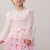 Pige iført lyserød langærmet kjole i plisseret tyl med flere lag