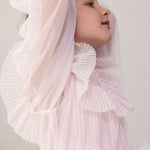 Pige iført lyserød langærmet kjole i plisseret tyl med flere lag