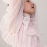 Pige iført lyserød langærmet kjole i plisseret tyl med flere lag