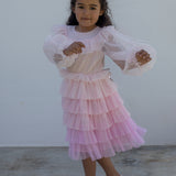 Pige iført lyserød langærmet kjole i plisseret tyl med flere lag