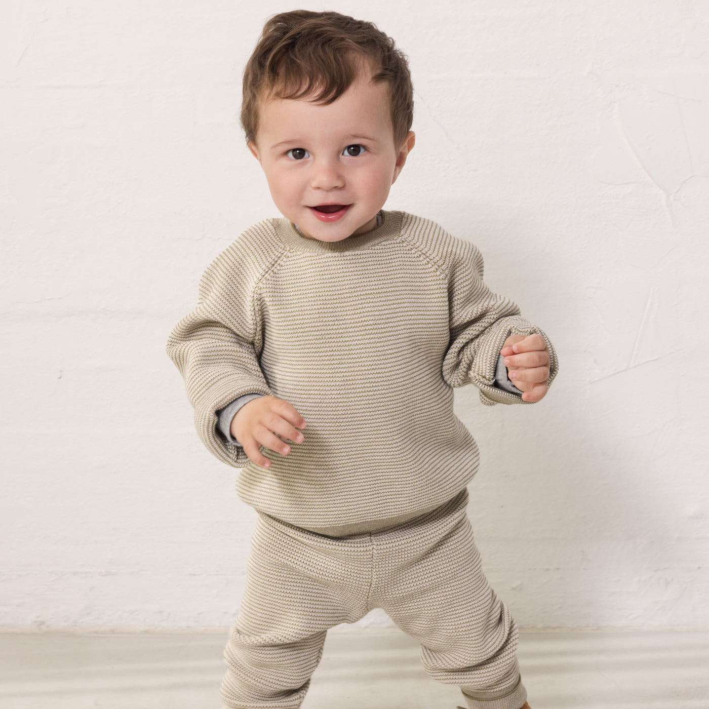 Baby iført beige strikket sæt med bluse og bukser