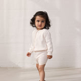 Pige iført strik cardigan med fint hulmønster og knaplukning og matchende shorts