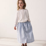 Pige iført lyseblå nederdel og hvid cardigan