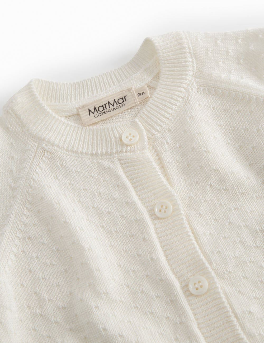 Hvid strik cardigan til baby, med fint hulmønster og knaplukning