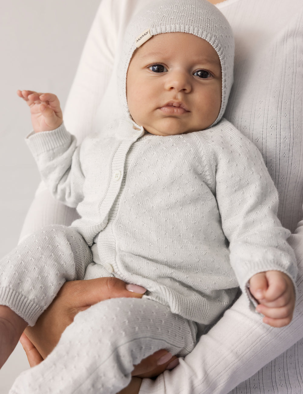 Baby iført lysgrønt sæt med cardigan, bukser og hue