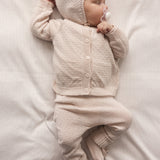 Baby iført lyserød cardigan, bukser og babyhue