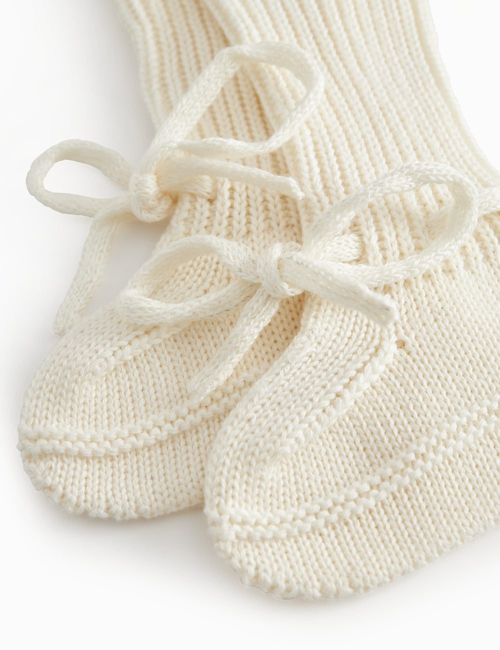 Strikkede babyfutter i råhvid med ribkant og bindebånd