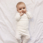 Baby i hvid baby bodystocking og bukser med små blomster