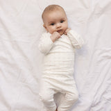 Baby i hvid baby bodystocking og bukser med små blomster