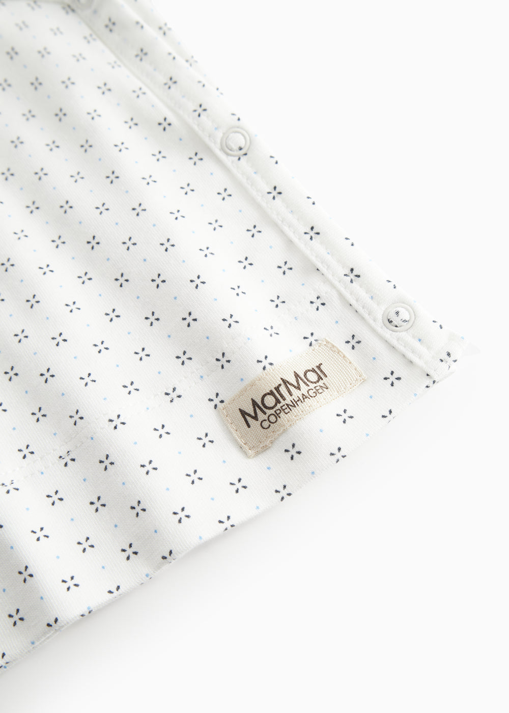 Hvid babybluse med slå-om lukning og fint mønster