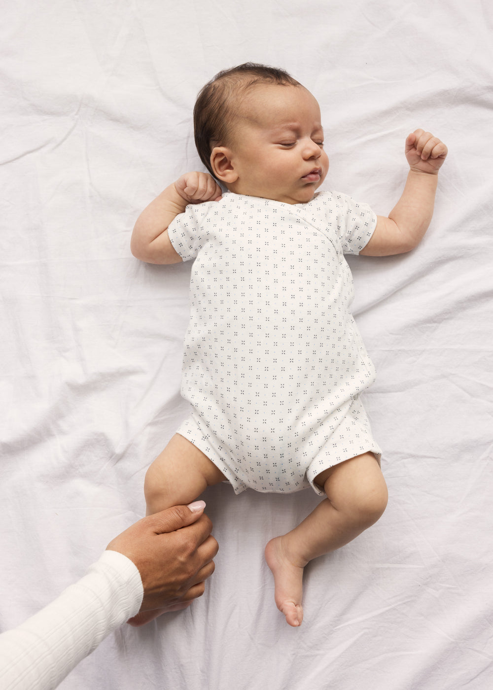 Baby der sover i hvid heldragt uden ben med fint mønster