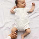Baby der sover i hvid heldragt uden ben med fint mønster