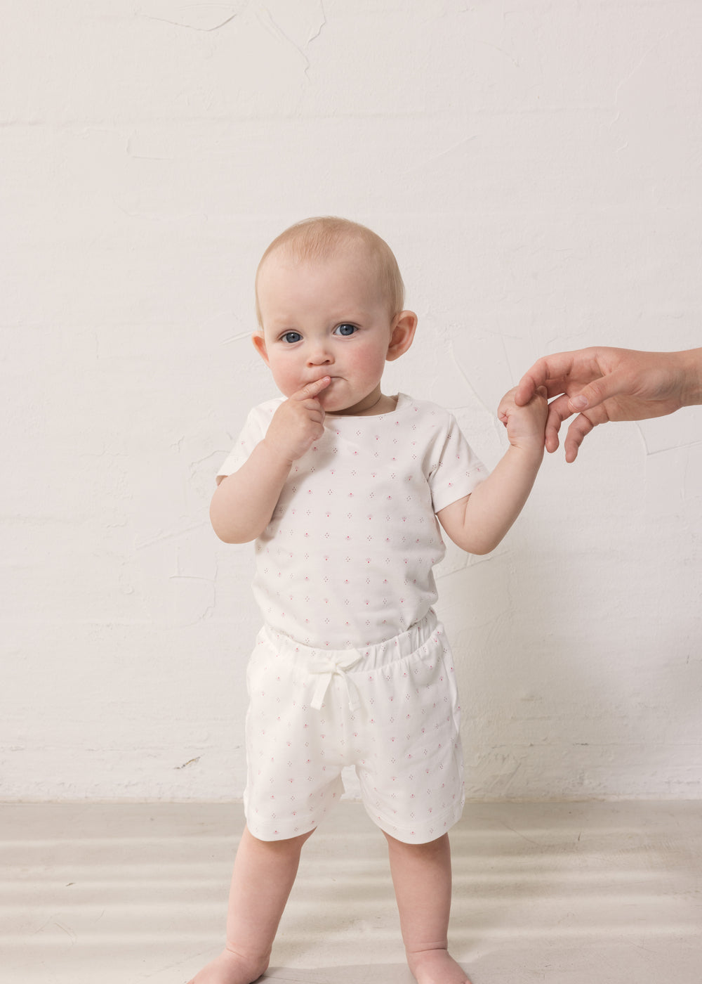 Baby i hvide shorts og bodystocking med små blomster