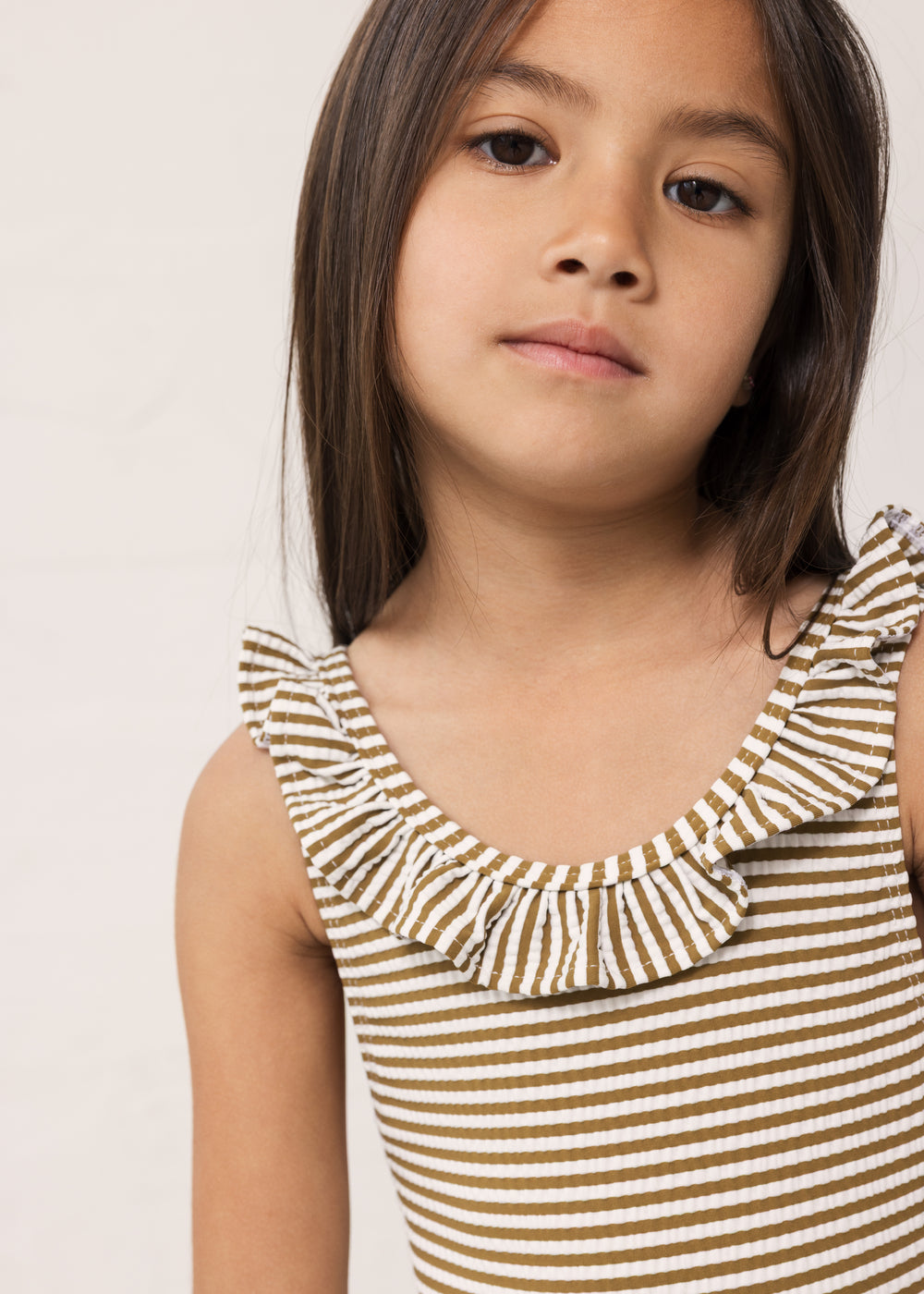 Pige i bronzefarvet stribet badedragt